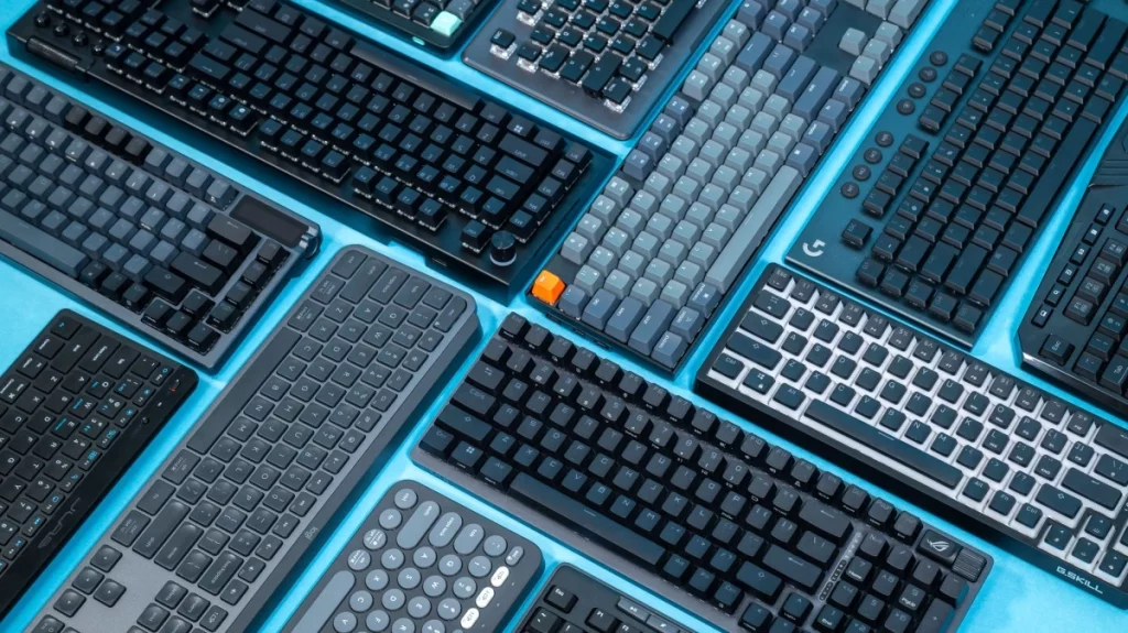 A variety of modern mechanical and wireless keyboards arranged on a blue background, showcasing some of the best keyboards for programming in 2025, including compact layouts, ergonomic designs, and models with customizable keys and RGB lighting.