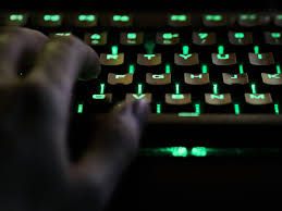 Close-up of a hand typing on a green backlit mechanical keyboard, highlighting a sleek and responsive setup ideal for late-night coding sessions.