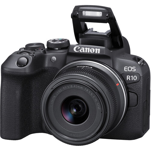 A three-quarter view of a black Canon EOS R10 mirrorless camera with an RF-S 18-45mm lens attached and its built-in flash extended.
