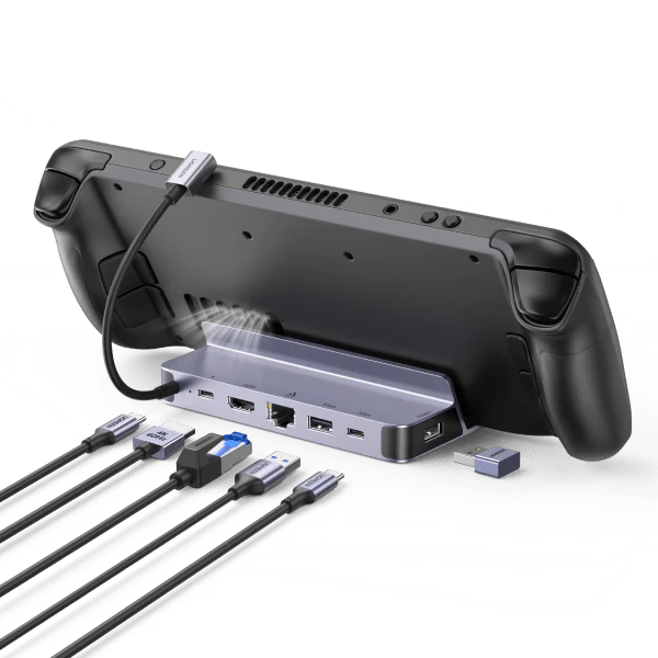 A black Steam Deck resting in a grey UGREEN 6-in-1 docking station. Multiple cables, including 4K HDMI and Ethernet, are plugged into the front ports to showcase its connectivity while keeping the console's air vents clear.