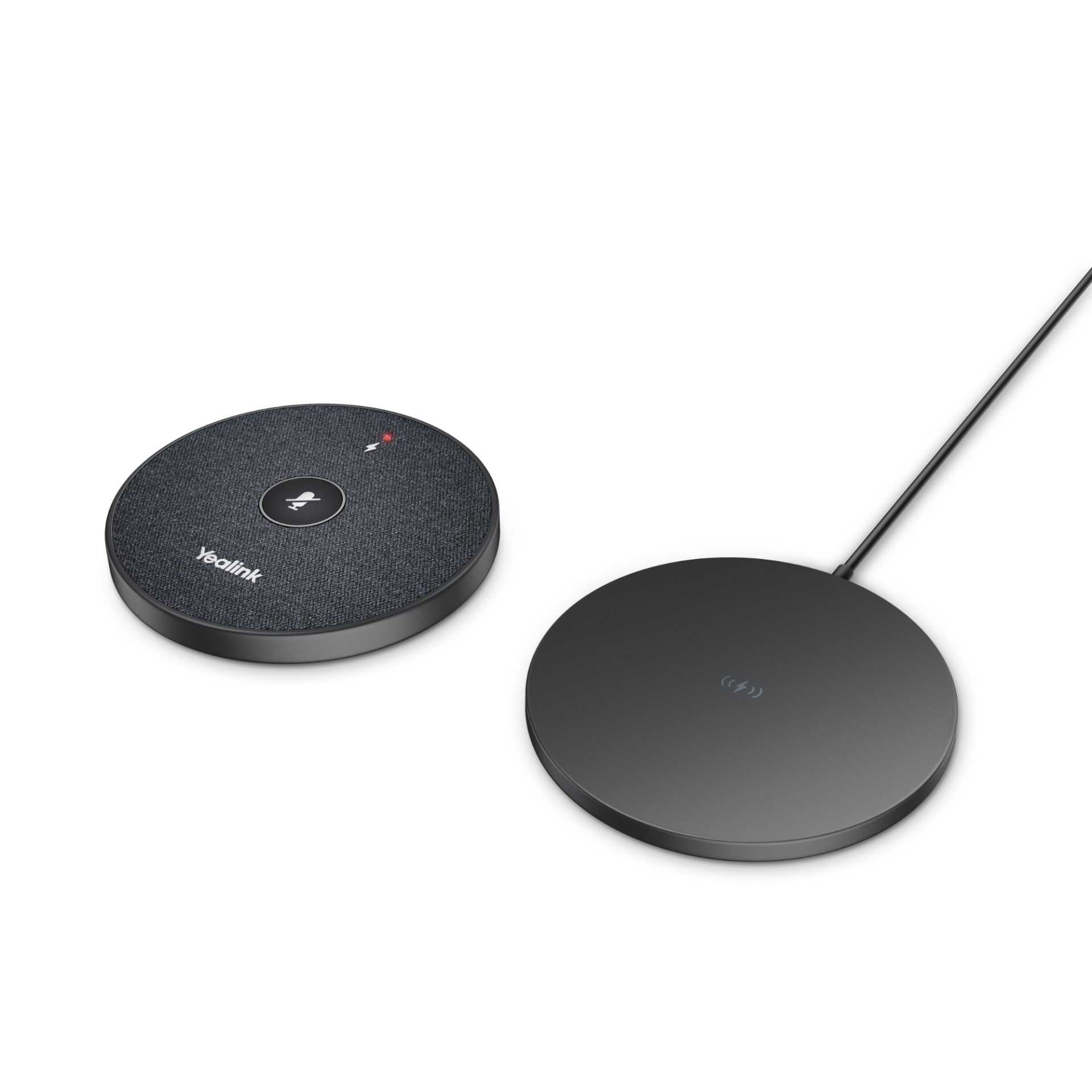 A top-down shot shows a round, dark gray Yealink microphone speaker on the left, next to a slightly larger, flatter, round, dark gray wireless charging pad on the right, both resting on a light gray surface.