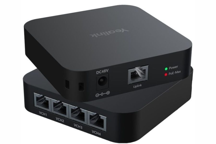 A pair of stacked, dark grey, square-shaped Yealink devices with rounded corners, presented at a slight angle. The top device is identical to the bottom, showing a DC48V power input, an Ethernet port labeled "Uplink", and two LED indicators: a green "Power" light and a red "PoE-Max" light. The top surface of the top device has the "Yealink" logo in white, oriented upside down. The front face of the bottom device features four Ethernet ports, labeled "VCH1", "VCH2", "VCH3", and "VCH4".