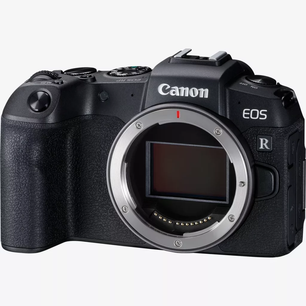 A close-up, three-quarter view of a black Canon EOS RP camera with no lens attached, showing the full-frame sensor and the metal lens mount ring. The top of the camera body, including the mode dial and power switch, is visible. The camera is isolated on a white background.