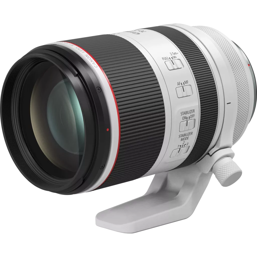 A three-quarter studio shot of a white Canon RF 70-200mm F2.8 L IS USM lens. The lens is equipped with a tripod collar and is resting on a clean white surface with a subtle shadow. The lens controls and rings are visible and well-defined, and the red ring, a hallmark of Canon's L-series lenses, is prominent.