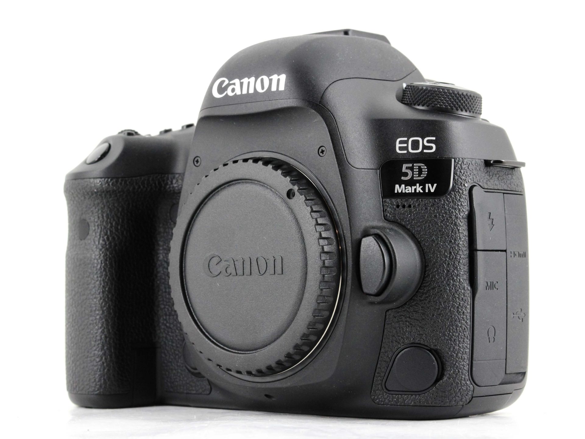 A front and side angled shot of a black Canon EOS 5D Mark IV DSLR camera body with the lens mount cap on. The camera has a textured grip on the right side and the "Canon" and "EOS 5D Mark IV" logos are clearly visible. The background is a solid white.