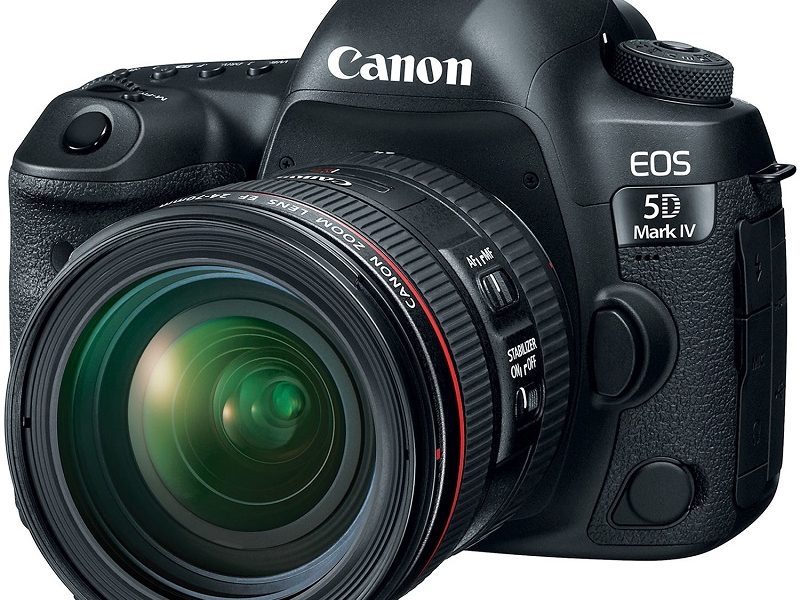 A professional product shot of a black Canon EOS 5D Mark IV DSLR camera with a Canon zoom lens attached. The camera is angled slightly to the right, showcasing the front of the lens and the body with "Canon" and "EOS 5D Mark IV" branding. The background is a solid white.