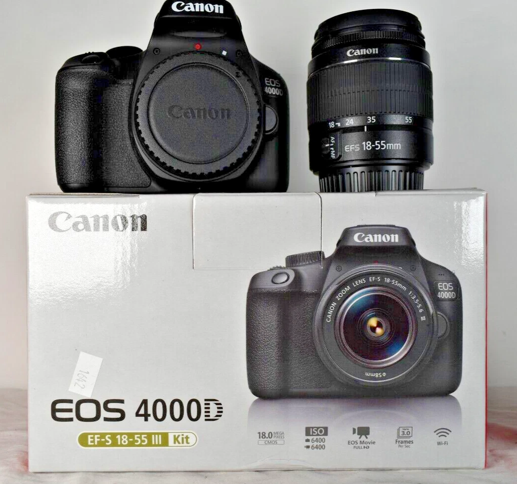 A black Canon EOS 4000D camera body and a Canon EF-S 18-55mm lens sit on top of a white box for the "EOS 4000D EF-S 18-55 III Kit." The camera body has a lens cap on and the lens is standing upright next to it. The box features an image of the camera with the lens attached and has "Canon" and "EOS 4000D" branding, along with some key specifications.